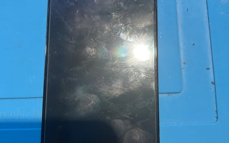 OPPO Reno5 更換用的螢幕總成放在藍色維修墊上，可見水滴型前鏡頭缺口與底部排線